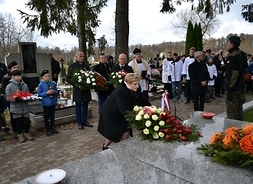 Elżbieta Lanc składa kwiaty na pomniku poległych żołnierzy, w tle uczestnicy wydarzenia