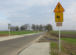 Zdjęcie przedstawia fragment przebudowanej drogi z chodnikami i oznaczeniami pionowymi