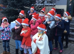 Przedszkolaki w czapkach świętego Mikołaja prezentują swoje talenty