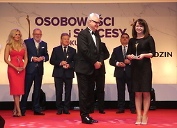 Zdjęcie przedstawia moment odebranie statuetki przez wicemarszałek Janinę Ewę Orzełowską z rąk Mariusza Pujszo. W tle nagrodzone osoby