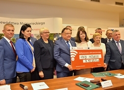 Przedstawiciele zarządu województwa mazowieckiego, mazowieckiej jednostki wdrażania programów unijnych i kolei pozują do zdjęcia z symbolicznym czekiem