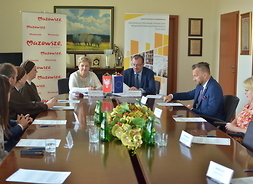przy stole, w sali konferencyjnej siedzą wicemarszałek Wiesław Raboszuk, członek zarządu Elżbieta Lanc oraz beneficjenci umów