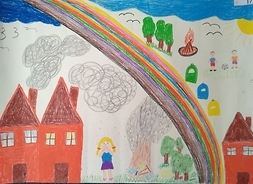 na zdjęciu widać kolorową tęczę, w tle domy oraz trójka dzieci