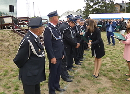 Strażacy stoją w linii, wicemarszałek Janina Ewa Orzełowska wręcza Dyplomy Uznania.