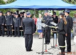 Podczas uroczystości dwóch strażaków stoi na przeciw siebie i salutuje