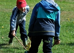 Dwóch chłopców bawi się drewnianymi zabawkami na trawie