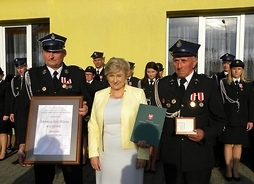 Elżbieta Lanc i dwóch strażaków, którzy trzymają medal