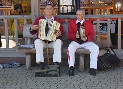 Dwóch mężczyzn w ludowych strojach grających na instrumentach muzycznych