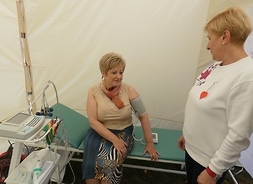 Elżbieta Lanc mierzy ciśnienie krwi, siedząc na łózku diagnostycznym w namiocie