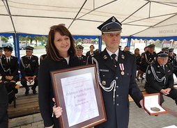 Wicemarszałek Janina Ewa Orzełowska stoi obok Prezesa OSP Jacka Jastrząbskiego, który trzyma Medal Pamiątkowy „Pro Masovia”