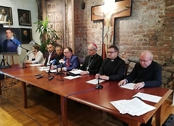 Za stołem konferencyjnym siedzą marszałek, dyrektor płockiej delegatury, biskup Piot Libera oraz księża