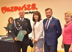w rzędzie stoją strażak, wicemarszałek Janina Ewa Orzełowska i 2 przedstawicieli podwarszawskich gmin
