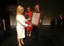 Rafał Rajkowski przekazuje medal na ręce dyrektor Agnieszki Stolarzyk