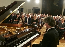 Pianista Paweł Kowalski przy fortepianie, w tle widac publiczność