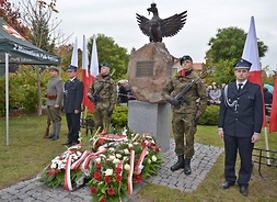 Pomnik z orłem z rozpostartymi skrzydłami. Przed pomnikiem leżą wieńce, a po obu stronach stoją dwaj żołnierze