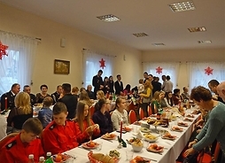 Uczestnicy siedzą za świątecznie udekorowanymi stołami