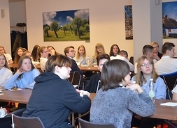 uczniowie z ostatniej klasy gimnazjalnej CXXXVII Liceum Ogólnokształcącego z Oddziałami Dwujęzycznymi  im. Roberta Schumana siedzą przy stołach, słuchają wykładu o regionie