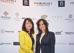 Janina Ewa Orzełowska, w tle biała ścianka z nazwami firm