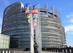 Budynek Parlamentu Europejskiego, siedziba główna, ujęcie z oddalenia, widać także maszty z flagami państw członkowskich Unii Europejskiej.