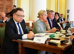Na pierwszym planie widać marszałka przy stole. W tle inni radni, m.in. członek zarządu Janina Ewa Orzełowska