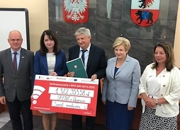 przedstawiciele samorzadu Mazowsza i powiatu węgrowskiego trzymają współnie symboliczny czek opiewający na kwotę 1,3 mln zł