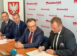 Krzysztof Ziółkowski, burmistrz Lubowidza w trakcie podspisywania umowy. Obok niego siedzą przedstawiciele mazowieckiego urzędu marszałkowskiego