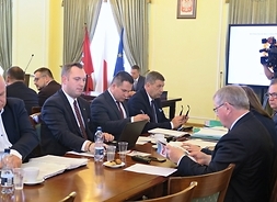 Po obu stronach długiego stołu siedzą radni - po jednej sami mężczyźni, po drugiej m.in. pan marszałek, członek zarządu Orzełowska