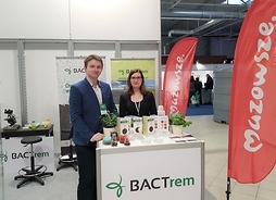 Dwoje przedstawicieli firmy BACTrem Sp. z o.o. stoi za ladą swojego firmowego stoiska prezentując materiały informacyjne.