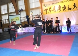 Koloro młodych sportowców prezentuje na scenie pokaz sztuk walki.