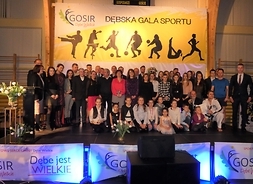 Zbiorowe zdjęcie pamiątkowe - kilkudziesięciu uczestników gali sportowej stoi na scenie w kilku rzędach.