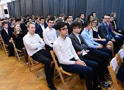 Kilkudziesięcioosobowa grupa uczniów z Zespołu Szkół Licealnych i Technicznych nr 1 w Warszawie - stypendystów marszałka siedzi w rzędach na krzesłach podczas spotkania.