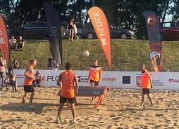 Czterech zawodników - po dwóch po przeciwnych stronach stołu gra w teqballa na plaży.