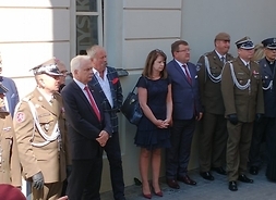 Członek zarządu Janina Ewa Orzełowska stoi wśród dużej grupy umundurowanych kombatantów