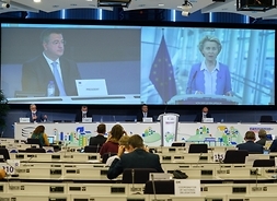 w ogólnym planie sala obrad Komitetu Regionów w Brukseli, uczestnicy patrza na wielki ekran na którym z lewej prowadzący obrady, z prawej przewodniczaca KE.