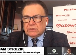 Na ekranie twarz i ramiona marszałka, za nim baner z logotypem samorządu Mazowsza.