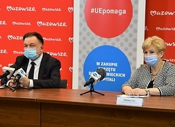 Za stołem siedzi dwoje uczestników konferencji, za nimi banery z lpgotypem samorządu Mazowsza.