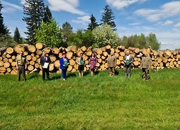 Uczestnicy spotkania na tle bali drewna
