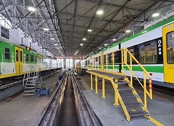 Wnętrze hali, w której znajdują się pociągi poddawane przeglądom. Po prawej i lewej stronie są długie pociągi kolei mazowieckich