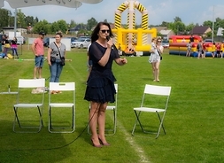 Kobieta przemawia stojąc na murawie boiska