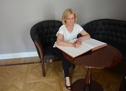 Maria Pakulnis przy stoliku wpisuje się do księgi pamiątkowej muzeum