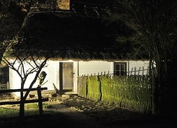 oświetlona nocą chata wiejska ze skansenu
