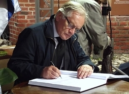 Aktor wpisujący się do księgi kondolencyjnej na pogrzebie Sławomira Mrożka w Krakowie