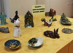 Stół zastawiony ceramicznymi figurkami zwierząt i talerzykami z motywami roślinnymi