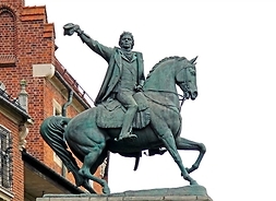 Spiżowa postać Kościuszki na koniu pozdrawiającego tłumy zdjętą rogatywką