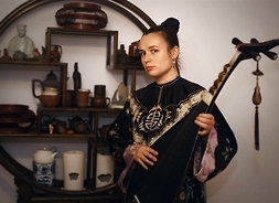 Artystka w tradycyjnym stroju chińskim przypominającym kimono z instrumentem strunowym w ręku
