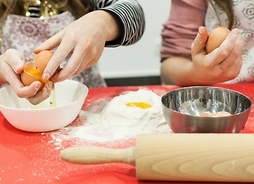 Ręce dzieci przygotowujących ciasto. Widać stosik mąki i żółtka jajek