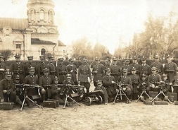 Duża grupa żołnierzy w polskich mundurach przedwojennych. Przed nimi na ziemi sześć karabinów
