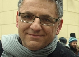 Portret dziennikarza w płaszczu i szaliku oraz okularach