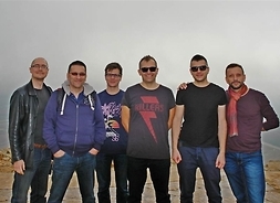 Sześciu muzyków na szczycie wzgórza w luźnych strojach i ciemnych okularach