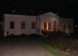 Parterowy budynek muzeum w półmroku, podświetlony latarniami